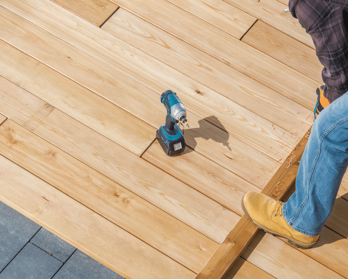 A skilled handyman installing a new deck in Greer, SC, using pressure-treated lumber and professional carpentry tools. The deck installer is measuring and securing deck boards, aligning joists, tightening fasteners, and building a sturdy outdoor platform. The image shows real deck construction work in progress with power drills, level, and safety gear, representing professional deck installation services, deck repair, and custom outdoor living upgrades in Greer and Greenville, South Carolina. Perfect example of high-quality deck building, structural reinforcement, and home improvement craftsmanship for homeowners needing reliable deck contractors and handyman services in the Upstate.